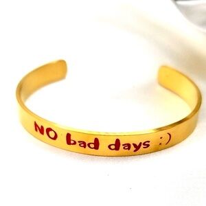 gold-tone cuff bracelet featuring the optimistic message "NO bad days :)"